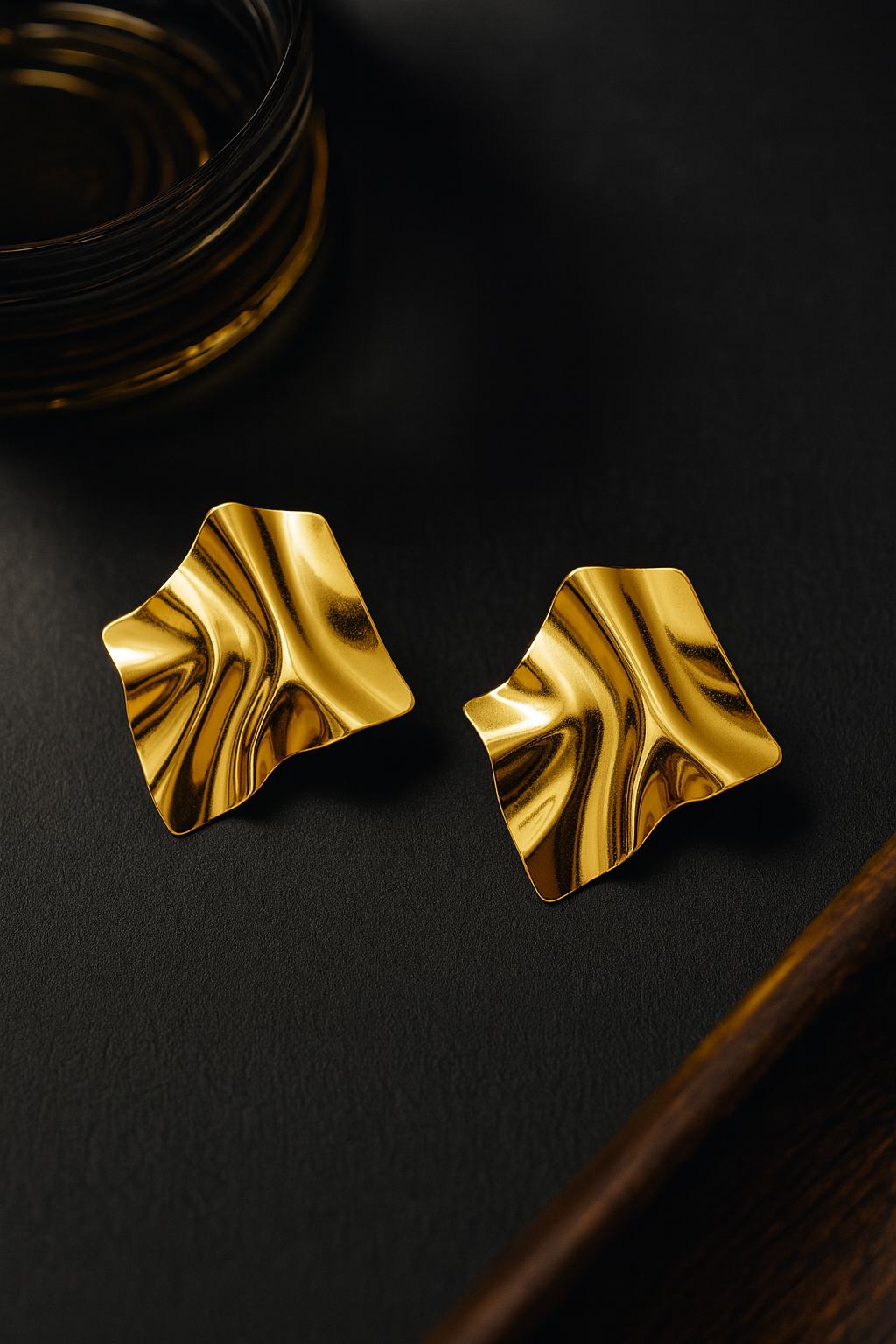 Abstract gold statement earrings with fluid wave-like texture and high-shine finish, modern sculptural design