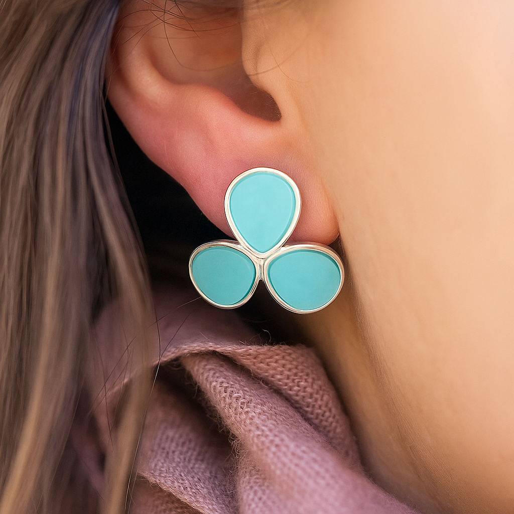 Close-up of a turquoise earring worn on an ear with a blurred background
