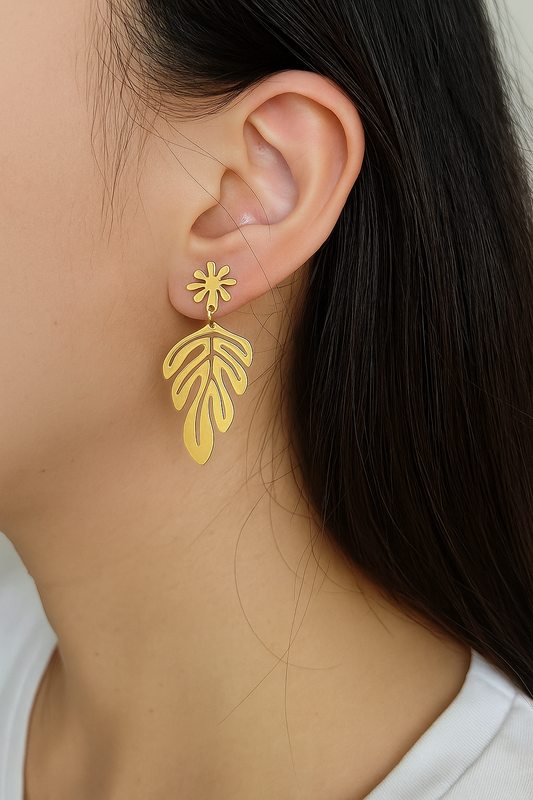 Contemporary gold drop earrings featuring abstract tropical leaf cutout and floral top, nature-inspired statement accessory