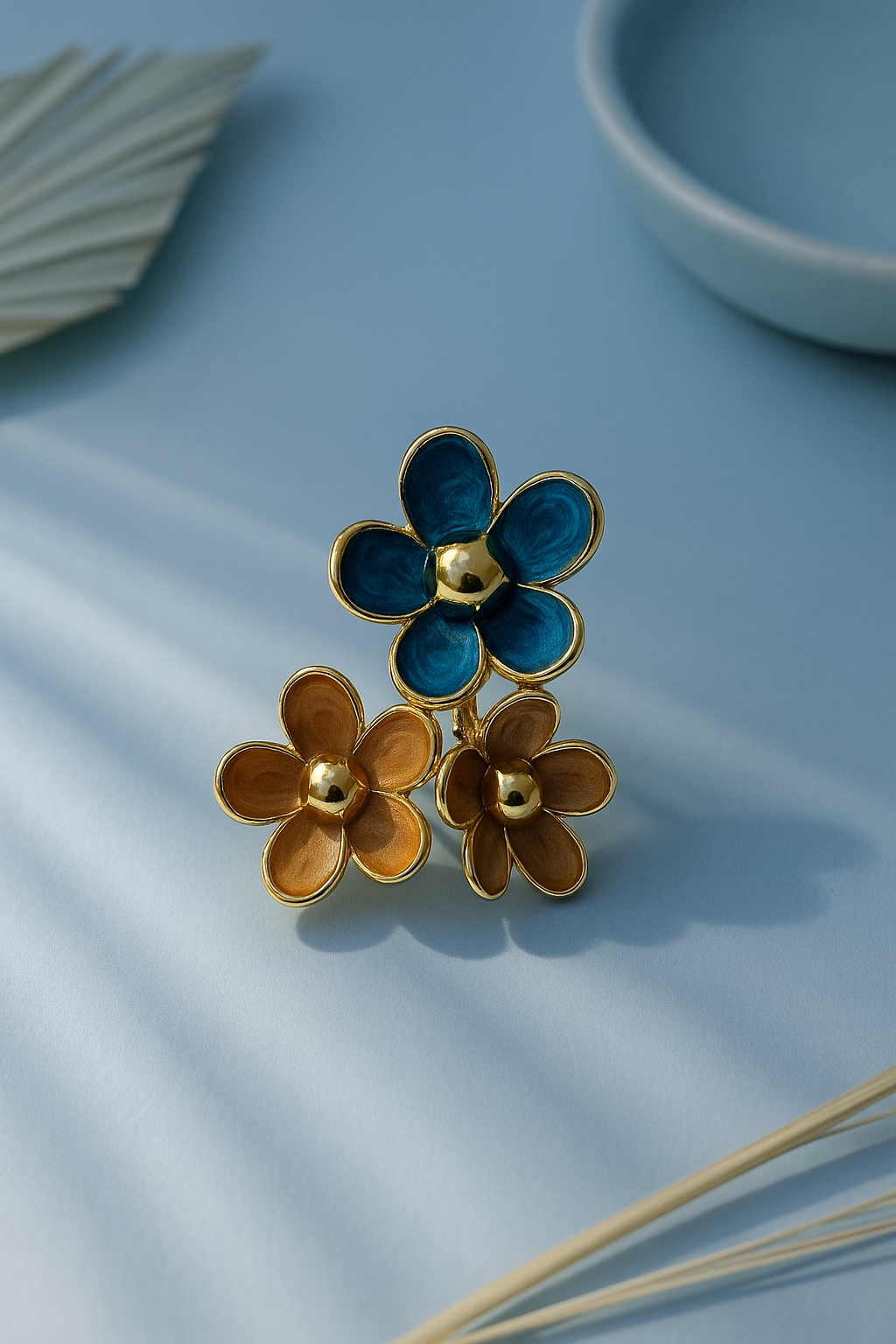 Gold and blue flower-shaped jewelry piece on a light blue surface