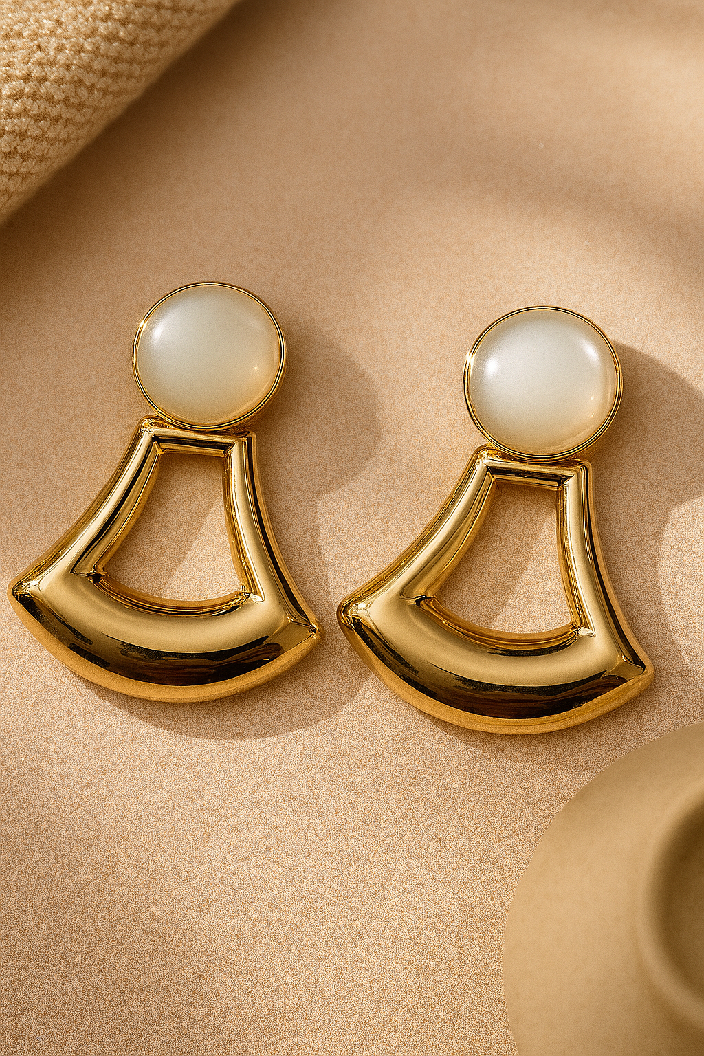 Polished gold geometric fan-shaped dangle earrings with white cabochon top, modern art deco style jewelry