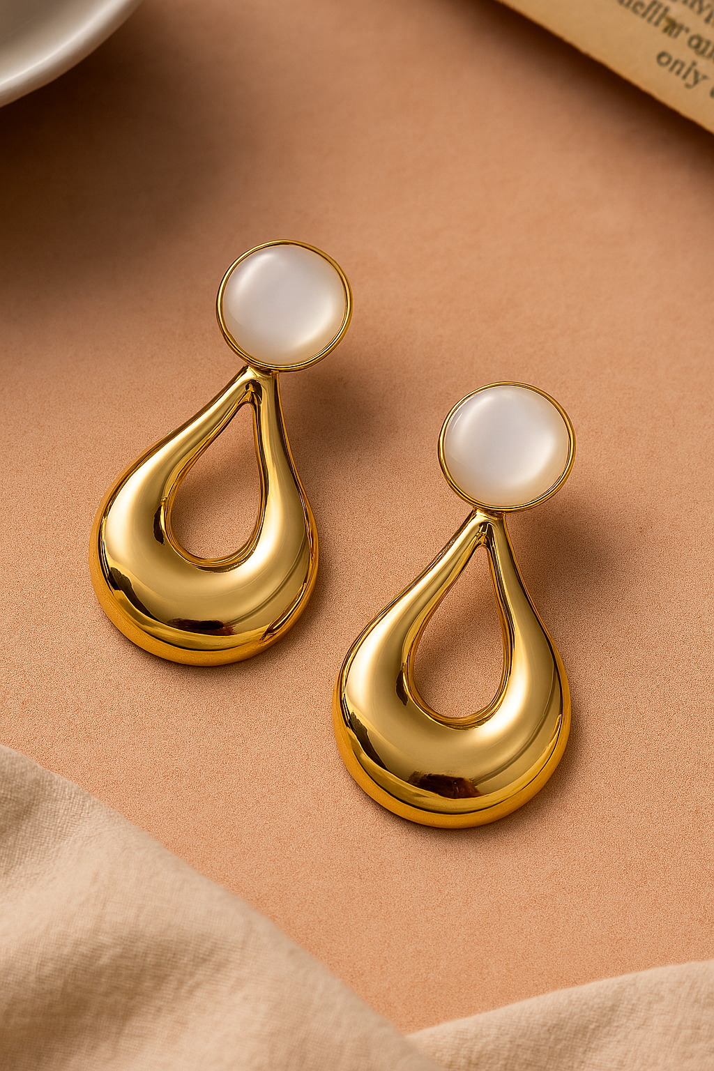 Polished gold teardrop dangle earrings with white pearl or stone top, elegant statement jewelry for women