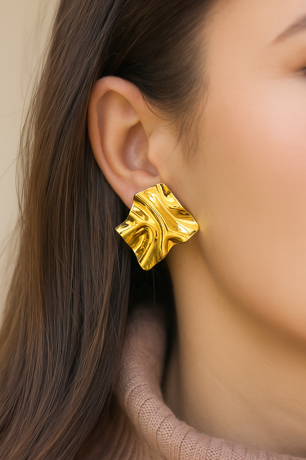 Designer gold earrings featuring folded, ripple-effect form in glossy metallic finish, bold and artistic accessory