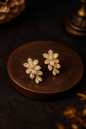Gold floral anti-tarnish earrings with crystal detailing on dark wood backdrop – perfect for weddings and festive wear