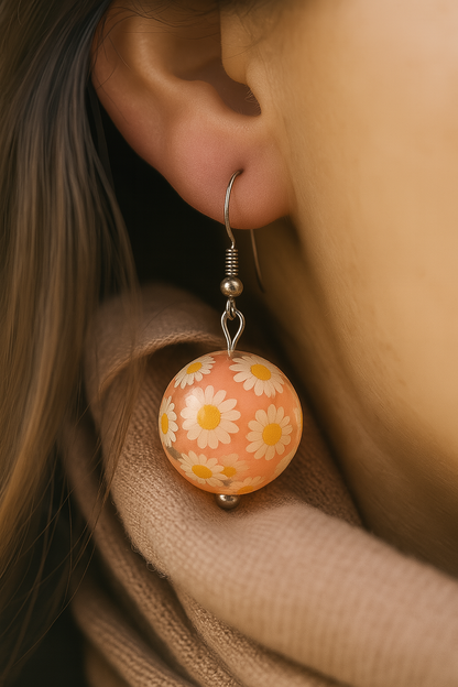 Handmade resin earrings with white daisy flowers on peach background in round drop design