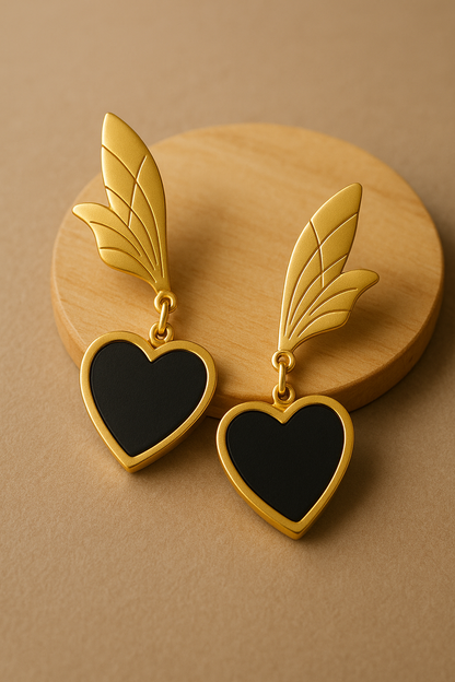 Matte gold anti-tarnish earrings with black heart drop and wing-inspired top design.
