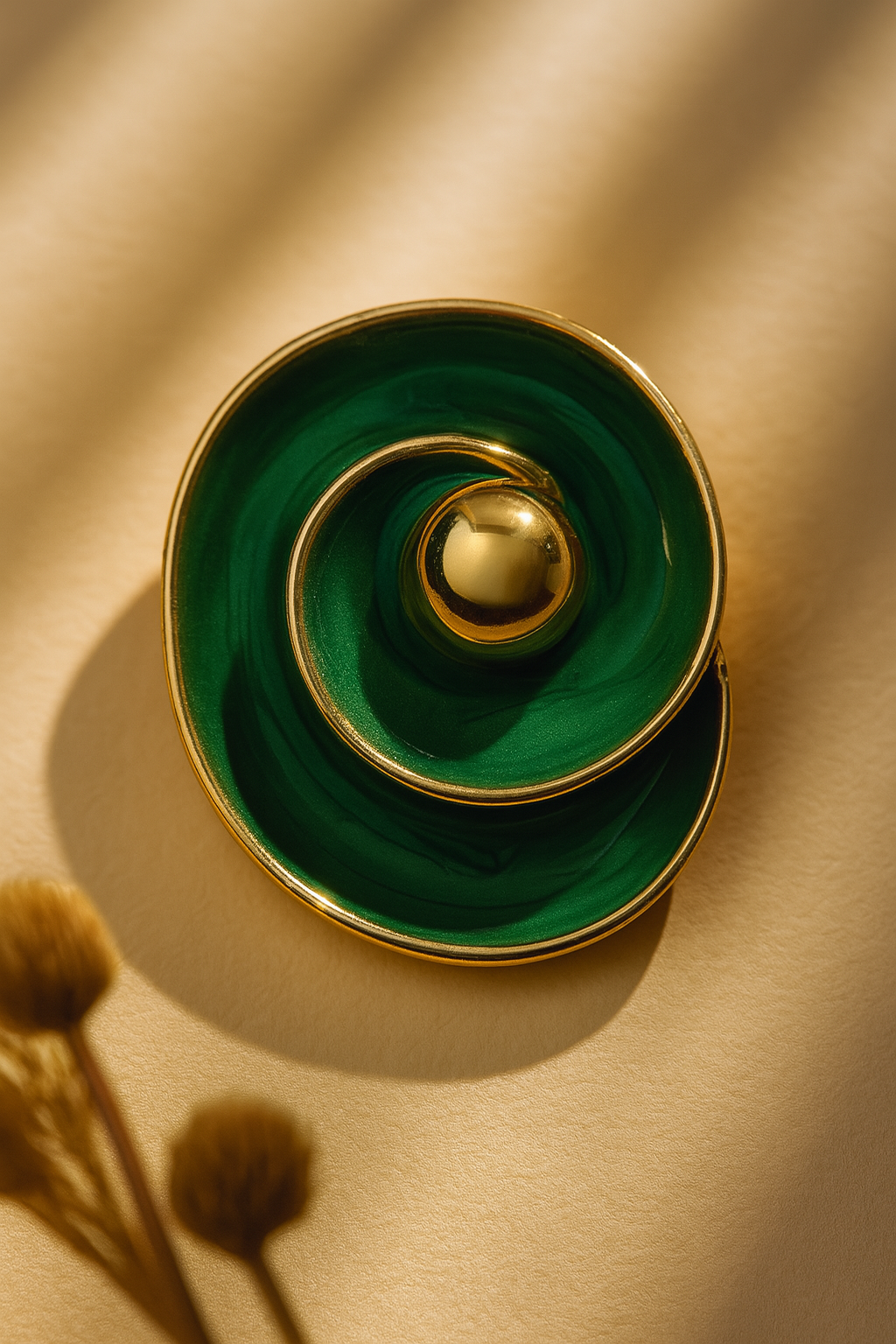 Modern gold-tone stud earrings with deep green swirling design